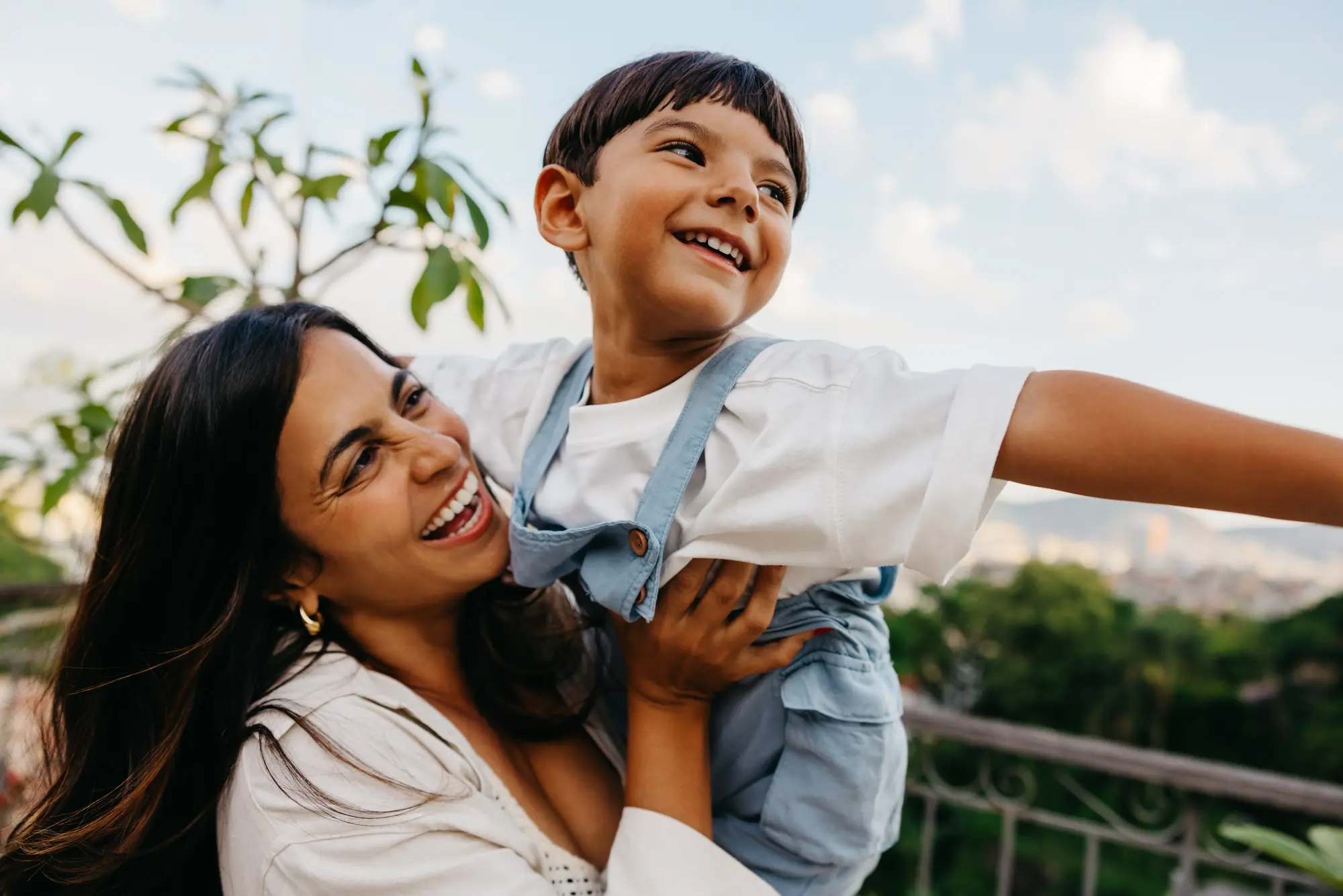 A mother and son laughing together outdoors in daylight